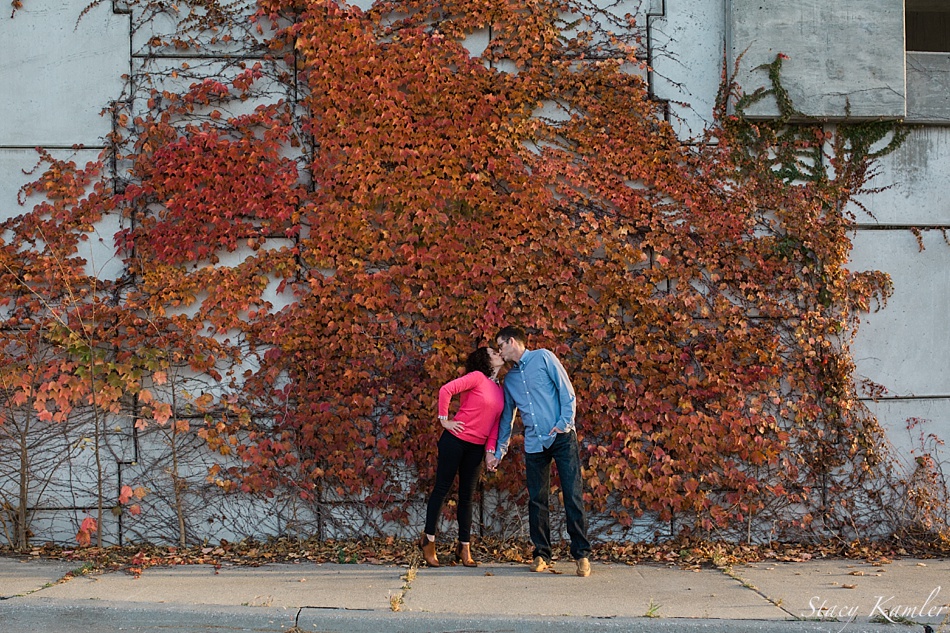 Engagement photos by fall leaves on a wall