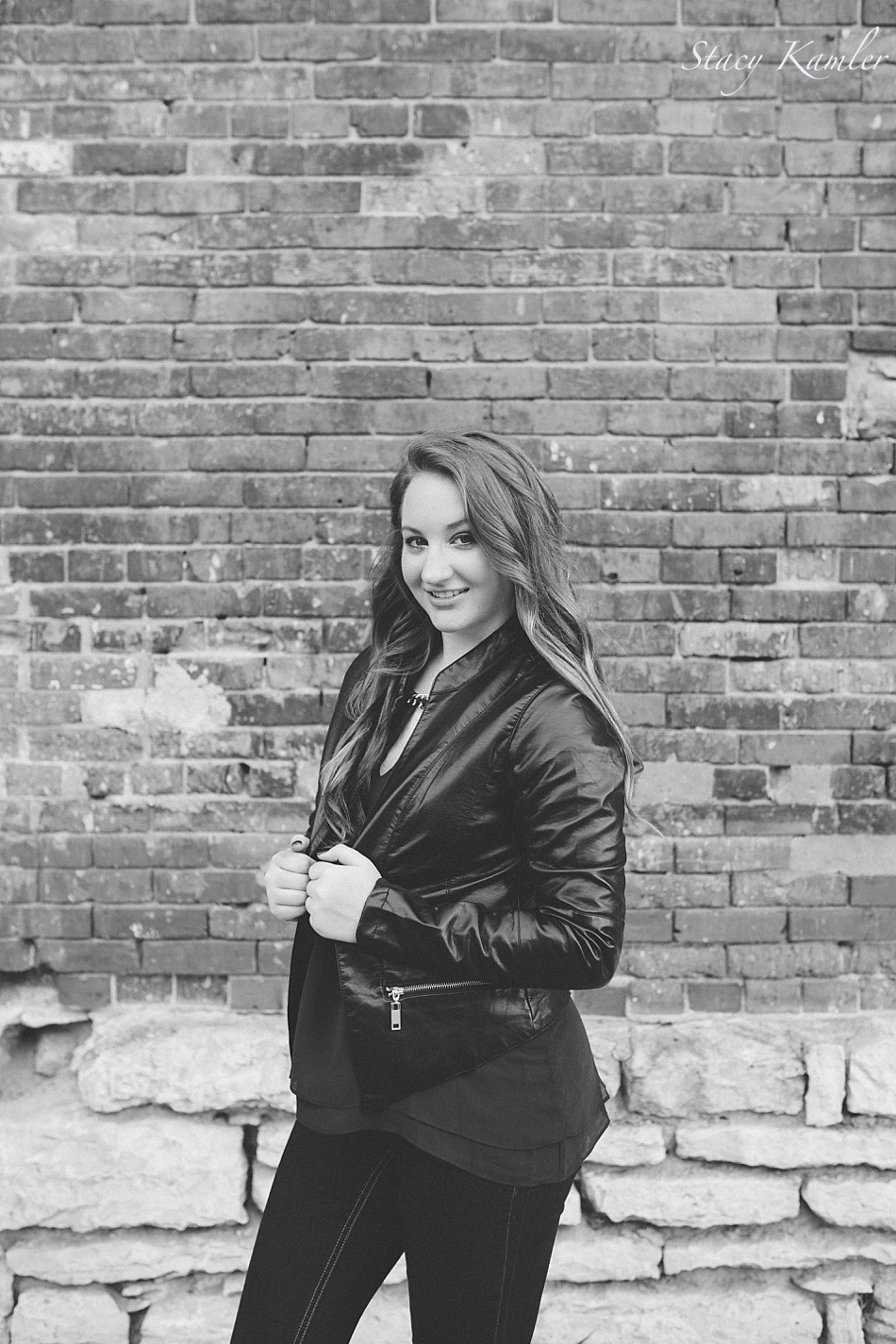 Senior girl in leather jacket against brick wall