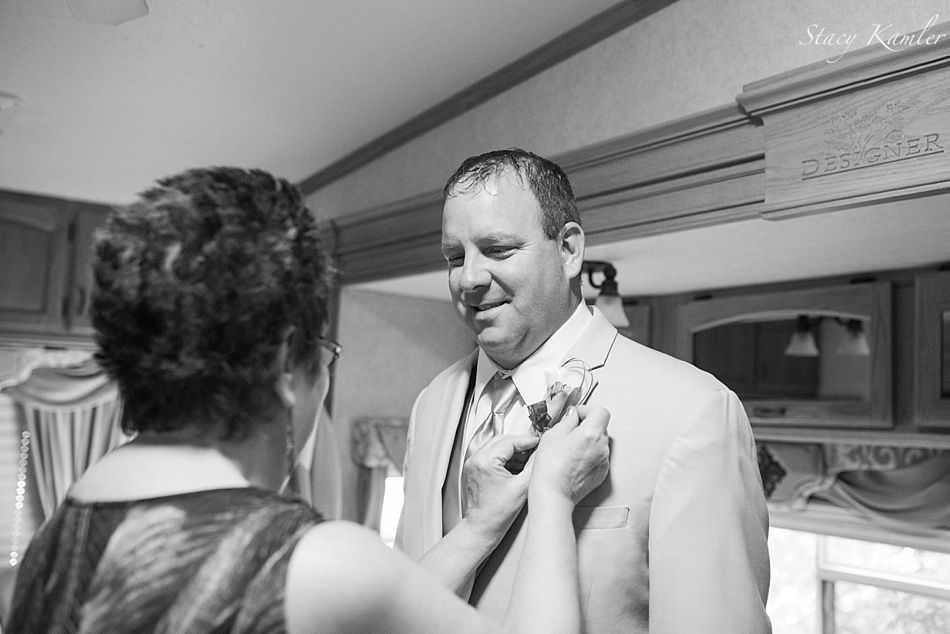 Groom getting boutonnière put on by mom