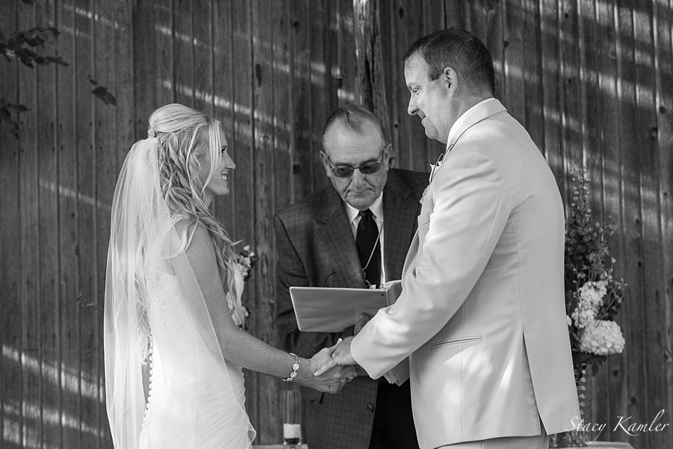 Bride and Groom exchanging vows in front of barn