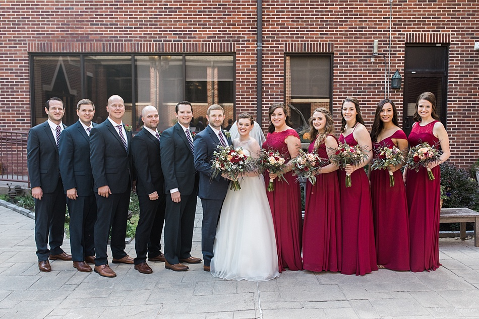 Bridal party with navy blue tuxes and red dresses