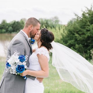 Bride and Groom kissing with veil blowing in wind