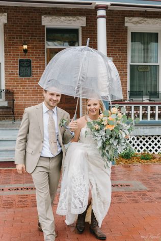Bride and Groom using a clear umbrella in the rain
