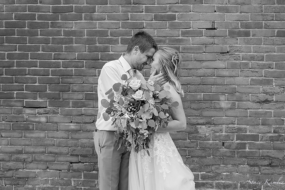 bride and groom portraits in front of brick wall