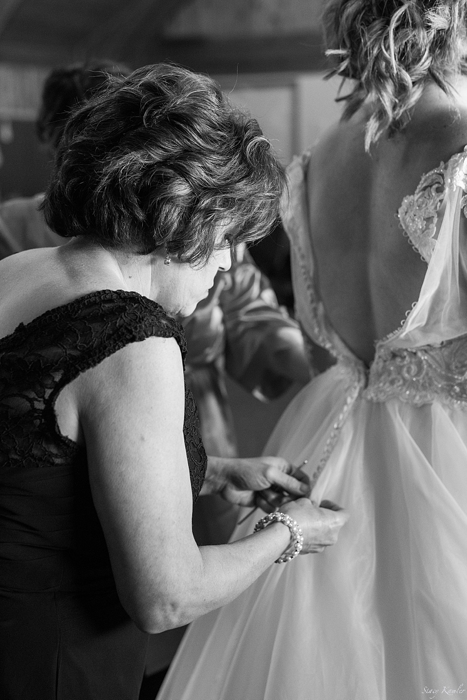 Mom buttoning up long sleeve wedding dress